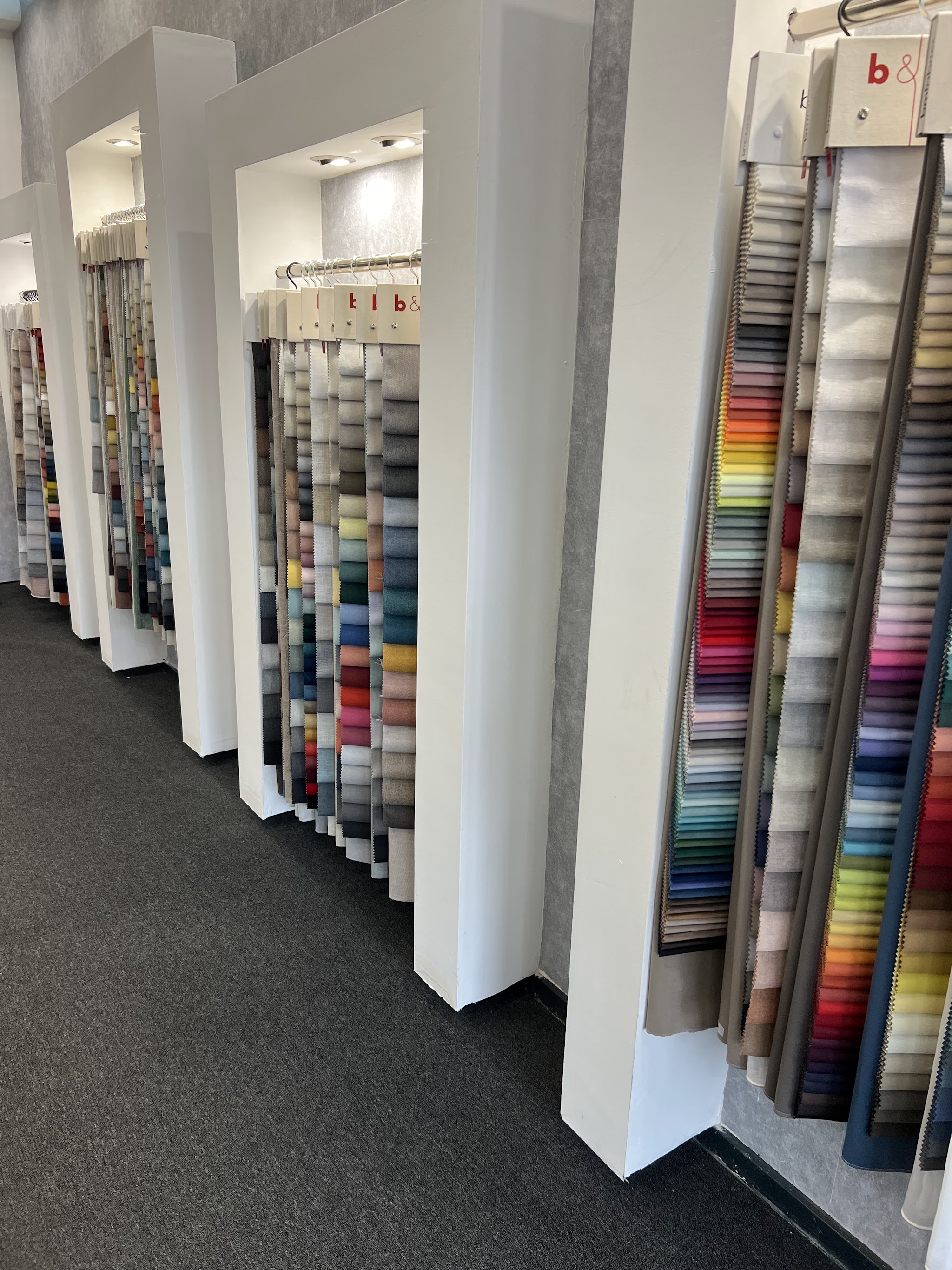 Wand met stalenboeken vol gordijnstoffen in alle kleuren