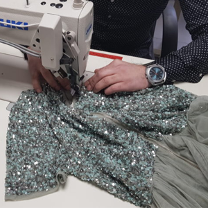 Aan de machine, werkend aan een met pailletten bezet kledingstuk