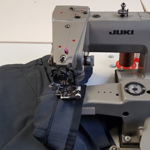Industriële Juki-naaimachine die een donkerblauwe broek zoomt