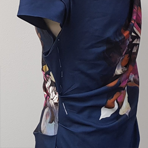 Donkerblauwe jurk met bloemenprint, opgespeld op een paspop